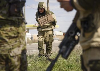 FILE - In this Thursday, April 23, 2015 file photo, a man with a poster around his neck reading "I am marauder, I beat and steal from civilians" is tied to a post by pro-Russian rebels who accused him of stealing from local people, next to a highway in Krasnyi Partyzan, Ukraine. (AP Photo/Mstyslav Chernov, File)
