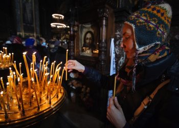 epa04548929 A woman lights a candle during the Orthodox Christmas Eve mass in St. Volodymir cathedral, Kiev, Ukraine, 06 January 2015. Christian Orthodox believers celebrate Christmas according to the Julian calendar on 06 January.  EPA/ROMAN PILIPEY
