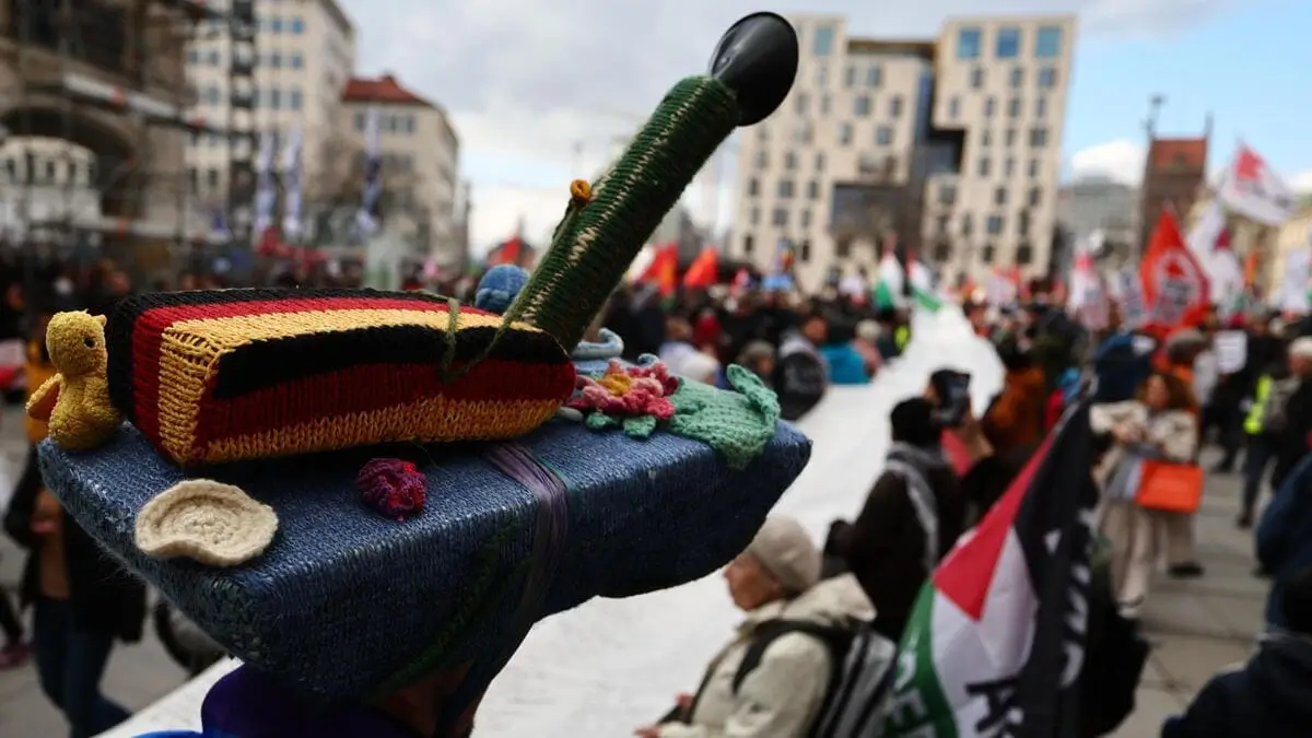 Un cittadino tedesco manifesta contro il riarmo indossando un cappello a forma di carro armato in Germania